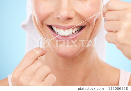 Floss, dental wellness and mouth of woman in studio for beauty, healthy face and happiness on blue background. Closeup model, tooth flossing and cleaning for facial smile, mint breath and happy teeth Floss, dental wellness and mouth of woman in studio for beauty, healthy face and happiness on blue background. Closeup model, tooth flossing and cleaning for facial smile, mint breath and happy teeth 132006538