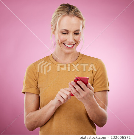Woman, phone and typing online for communication, social media and chat on pink background. Happy mature model with smartphone in hands for network connection or writing post on mobile app website 132006571