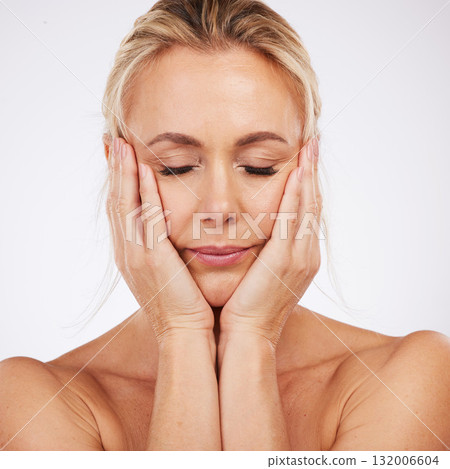 Hands, face and beauty with a mature woman in studio on a gray background touching her soft, smooth skin. Spa, facial and antiaging with a female posing eyes closed for natural skincare or cosmetics Hands, face and beauty with a mature woman in studio on a gray background touching her soft, smooth skin. Spa, facial and antiaging with a female posing eyes closed for natural skincare or cosmetics 132006604