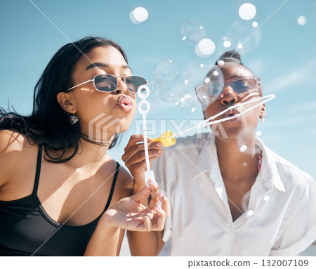 Woman, friends, and blowing bubbles by beach, ocean or sea on summer vacation, holiday travel or bonding activity. Women playing with soap or bubble wand or toy in fun game, freedom or social break Woman, friends, and blowing bubbles by beach, ocean or sea on summer vacation, holiday travel or bonding activity. Women playing with soap or bubble wand or toy in fun game, freedom or social break 132007109