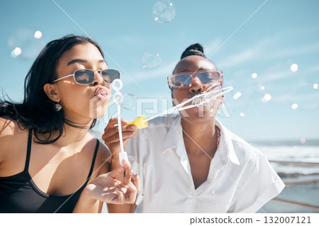 Friends, playing or blowing bubbles by beach, ocean or sea in summer holiday, travel vacation or bonding activity. Women, people or students and soap wand or toy in fun game, freedom or social break Friends, playing or blowing bubbles by beach, ocean or sea in summer holiday, travel vacation or bonding activity. Women, people or students and soap wand or toy in fun game, freedom or social break 132007121