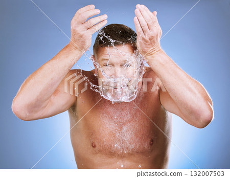 Man, water splash and face wash for skincare hygiene or natural sustainability against a blue studio background. Male washing for clean health and wellness in self love or care for facial treatment Man, water splash and face wash for skincare hygiene or natural sustainability against a blue studio background. Male washing for clean health and wellness in self love or care for facial treatment 132007503