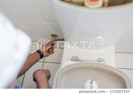 Toilet maintenance, plumber hands and contractor fix of a renovation employee in the bathroom. Home improvement, development and house repair of industrial pipe and construction worker doing a job Toilet maintenance, plumber hands and contractor fix of a renovation employee in the bathroom. Home improvement, development and house repair of industrial pipe and construction worker doing a job 132007547