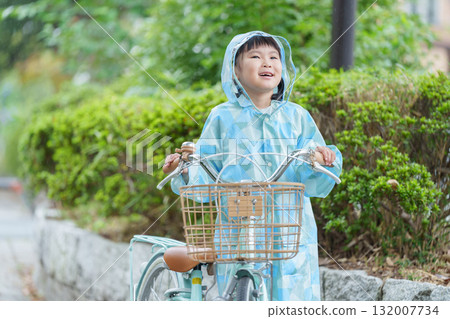 A child riding a bicycle in a raincoat on a rainy day A child riding a bicycle in a raincoat on a rainy day 132007734