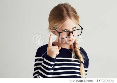 Strict, serious and portrait of a child with a gesture isolated on a white background in a studio. Rude, smart and a young girl wearing glasses and gesturing with finger for discipline on a backdrop 132007828