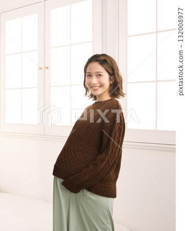 Pregnant woman standing by the window 132008977