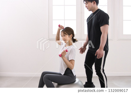 Young woman receiving training from a personal trainer 132009017