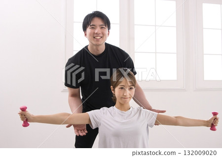 Young woman receiving training from a personal trainer 132009020