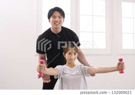 Young woman receiving training from a personal trainer Young woman receiving training from a personal trainer 132009021