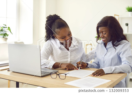 African american office friendly workers, women cooperating on new project, sitting at work desk African american office friendly workers, women cooperating on new project, sitting at work desk 132009353