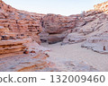 Visitors navigate through Tsvetnoy Canyon in Egypt, admiring the unique rock formations and sandy terrain under clear skies. 132009460