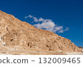Golden rock formations rise majestically against a backdrop of fluffy white clouds and a bright blue sky in the Sinai desert 132009465