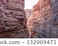 Visitors admire the breathtaking rock walls of Tsvetnoy Canyon, where colors illuminate the rugged landscape as sunlight begins to set. 132009471