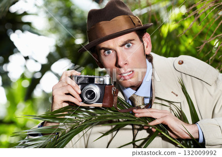 Retro spy man, camera and jungle for investigation, inspection or journalist with shock at job. Private investigator, secret photographer and retro paparazzi in trees, bush or leaves for surveillance 132009992