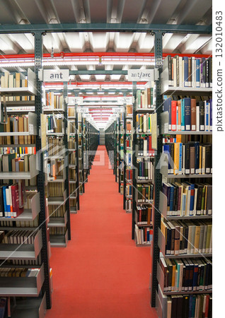 An aisle lined with books neatly stored on shelves in a library 132010483