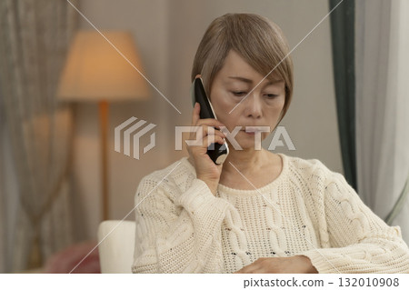Senior woman responding to suspicious phone call at home Senior woman responding to suspicious phone call at home 132010908