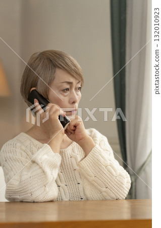 Senior woman responding to suspicious phone call at home 132010923