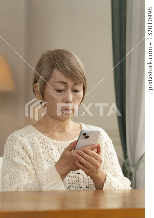 A senior woman responding to a suspicious call on her mobile phone 132010998
