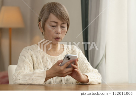 A senior woman responding to a suspicious call on her mobile phone 132011005