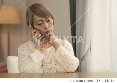 A senior woman responding to a suspicious call on her mobile phone A senior woman responding to a suspicious call on her mobile phone 132011012