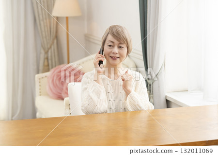Senior woman happily chatting on the phone at home Senior woman happily chatting on the phone at home 132011069