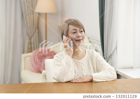 Senior women happily chatting and searching on their smartphones Senior women happily chatting and searching on their smartphones 132011129