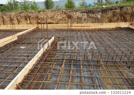 Steel reinforcement is placed in wooden molds and formwork on a construction site  132011224