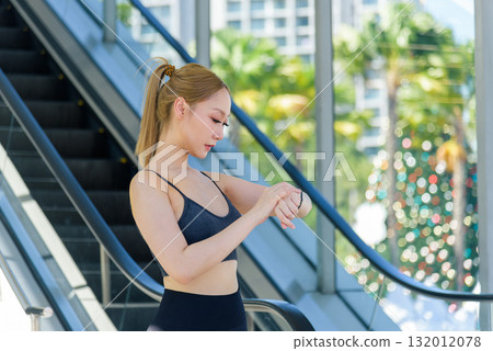 Workout focused woman checks smart watch, tracking fitness progress, preparing for active exercise outdoor. Sporty lifestyle supports wellbeing, leading to successful workout performance. 132012078