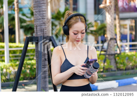 Fit sport woman workout outdoor, people exercise, using phone, water for next workout session, remaining active and hydrated. Fit sport woman workout outdoor, people exercise, using phone, water for next workout session, remaining active and hydrated. 132012095
