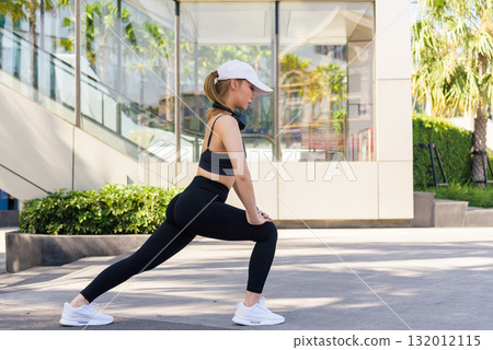 Fit woman performs sport exercise workout outdoor stretching leg for healthy body demonstrating strong fit physique promoting active lifestyle for people in urban city. 132012115