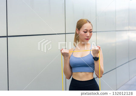 Exercise woman sport workout, fit person does outdoor stretch exercise with resistance band, achieving strength and health goals for active lifestyle. 132012128