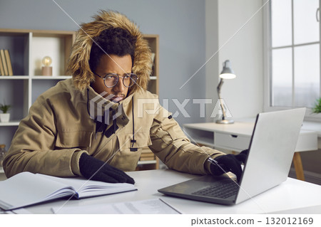 Freezing man in warm jacket and gloves working at computer in office 132012169