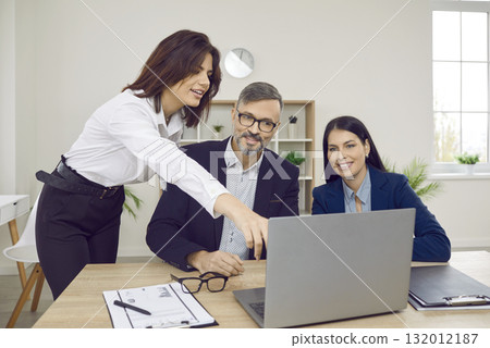 woman employee showing something to her colleagues on the monitor screen on workplace in office. woman employee showing something to her colleagues on the monitor screen on workplace in office. 132012187