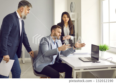 Man talking to his business colleagues and showing something on a laptop computer Man talking to his business colleagues and showing something on a laptop computer 132012190