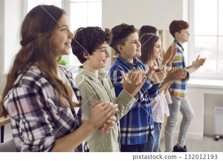 Group of happy elementary school boys and girls clapping hands at a school event Group of happy elementary school boys and girls clapping hands at a school event 132012193
