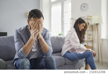 Upset married couple sitting silently on sofa facing away from each other 132012206