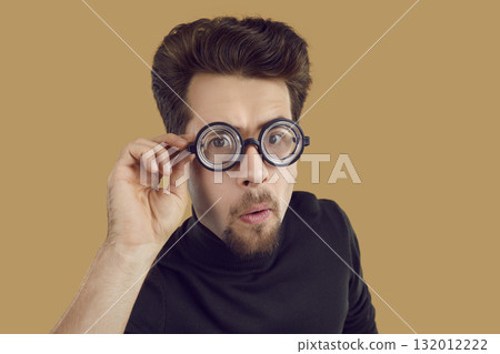 Portrait of funny alert and curious man looking at you through glasses with enlarged lenses. Portrait of funny alert and curious man looking at you through glasses with enlarged lenses. 132012222