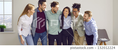 Banner with a happy diverse business team standing in the office, huddling, and smiling Banner with a happy diverse business team standing in the office, huddling, and smiling 132012224