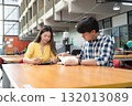 Young Asian students using laptop, learning and discussing in a library at the university. 132013089