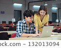 Young Asian students using laptop, learning and discussing in a library at the university. 132013094