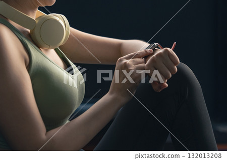 Young Asian woman in sportswear checking her workout results on a smart watch while resting at the gym. Young Asian woman in sportswear checking her workout results on a smart watch while resting at the gym. 132013208