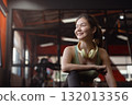 Fitness, happy woman and ready in gym with headphones, relax for workout, smile and music for exercise. 132013356