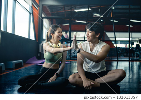 Happy young man and woman high five for success or good exercise and well done gesture for reaching fitness goal. Active trainer and client woman celebrating a great workout, training or exercising. 132013357