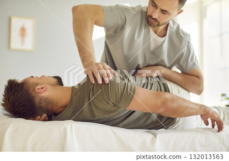 Professional chiropractor or physical therapist performs manual therapy session with male patient. 132013563