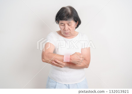 Elderly Woman having wrist pain with Medicated pain relief patch plaster for Carpal Tunnel Syndrome, Wrist Tendinitis, muscle ache, De Quervain s tenosynovitis, Hand Osteoarthritis and Senior health Elderly Woman having wrist pain with Medicated pain relief patch plaster for Carpal Tunnel Syndrome, Wrist Tendinitis, muscle ache, De Quervain s tenosynovitis, Hand Osteoarthritis and Senior health 132013921
