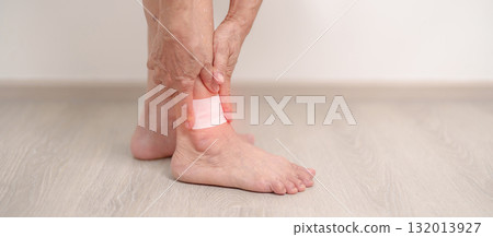 Elderly woman having leg pain with Medicated pain relief patch plaster for Ankle Sprains or Achilles Tendonitis and Shin Splints ache. injury, hyperuricemia disease, Gout and Senior Health care 132013927