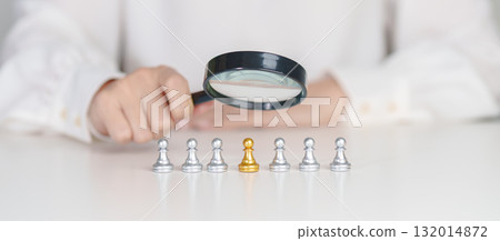 Businesswoman hand holding magnifying glass for recruiting leader man chess from crowd of employees.Human resource management, Recruitment, Teamwork, hiring and leadership Concepts 132014872