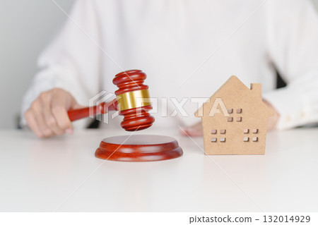 Real Estate Law, Home Insurance, property Tax, Auction and Bidding concepts. small toy house model with gavel justice hammer on desk in courthouse 132014929