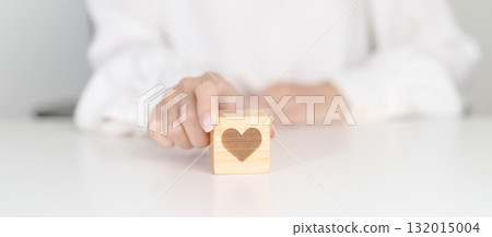 Hand holding heart block for health care, love, organ donation, charity, happy family, wellbeing and insurance concepts. world heart day, health day and mental health day Hand holding heart block for health care, love, organ donation, charity, happy family, wellbeing and insurance concepts. world heart day, health day and mental health day 132015004