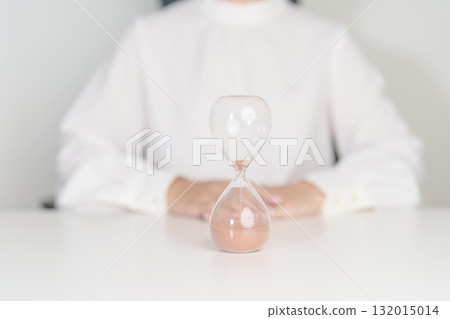 Woman with Hourglass on table office, Sand flowing through the bulb of Sandglass measuring the passing time. countdown, deadline, Life time and Retirement concept Woman with Hourglass on table office, Sand flowing through the bulb of Sandglass measuring the passing time. countdown, deadline, Life time and Retirement concept 132015014
